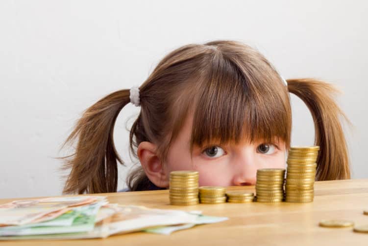 Ein kleines Mädchen beobachtet Geld auf Tisch