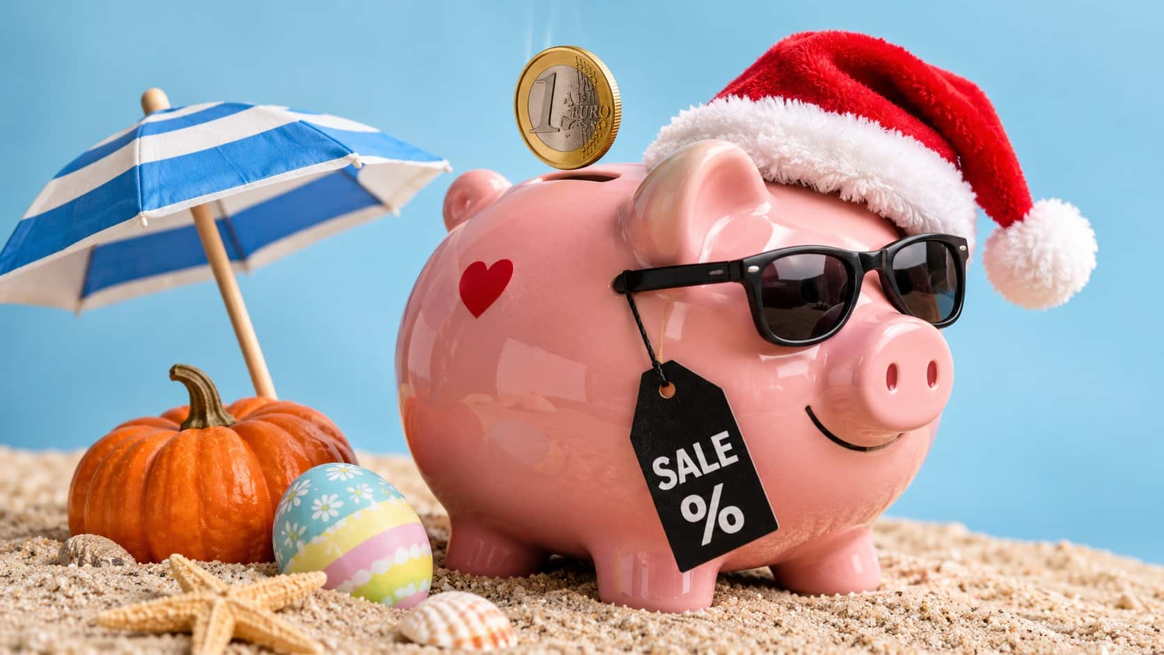 Rosa Sparschwein mit Weihnachtsmütze, Sonnenbrille und SALE-Preisschild, in das eine Euromünze fällt. Daneben stehen ein Sonnenschirm, ein Kürbis und ein Osterei als Symbole für saisonale Rabattaktionen.